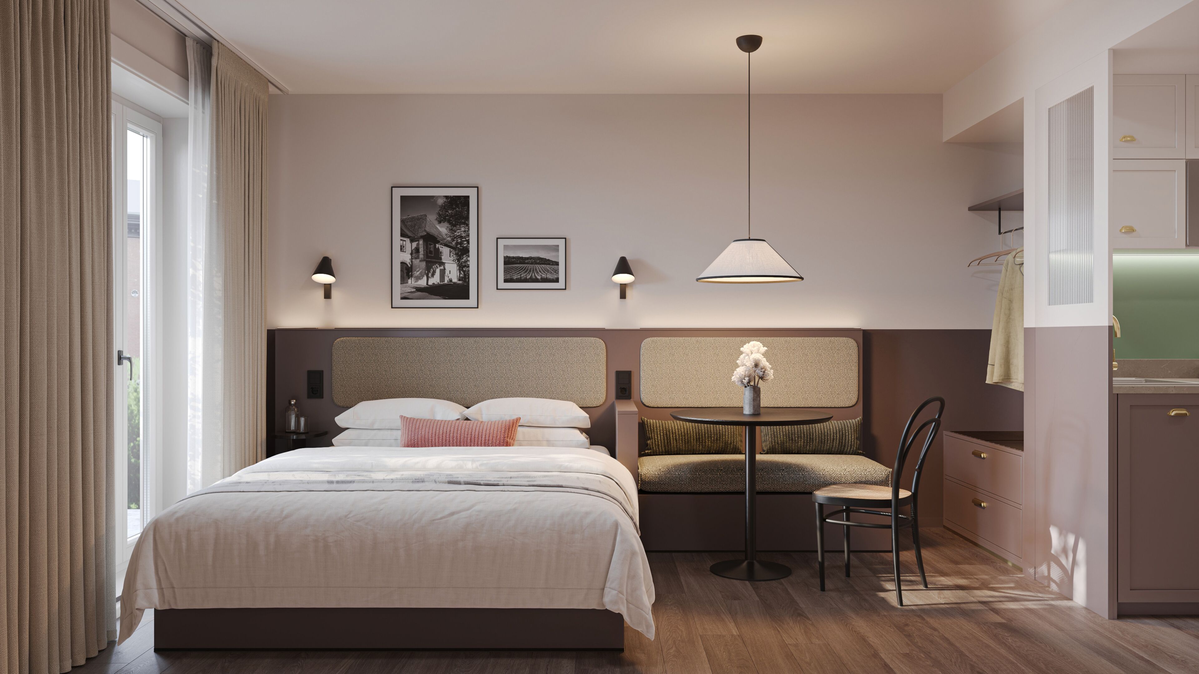 A hotel room with a bed, a small table with a chair, a sofa, a wall-mounted lamp, and a framed picture.