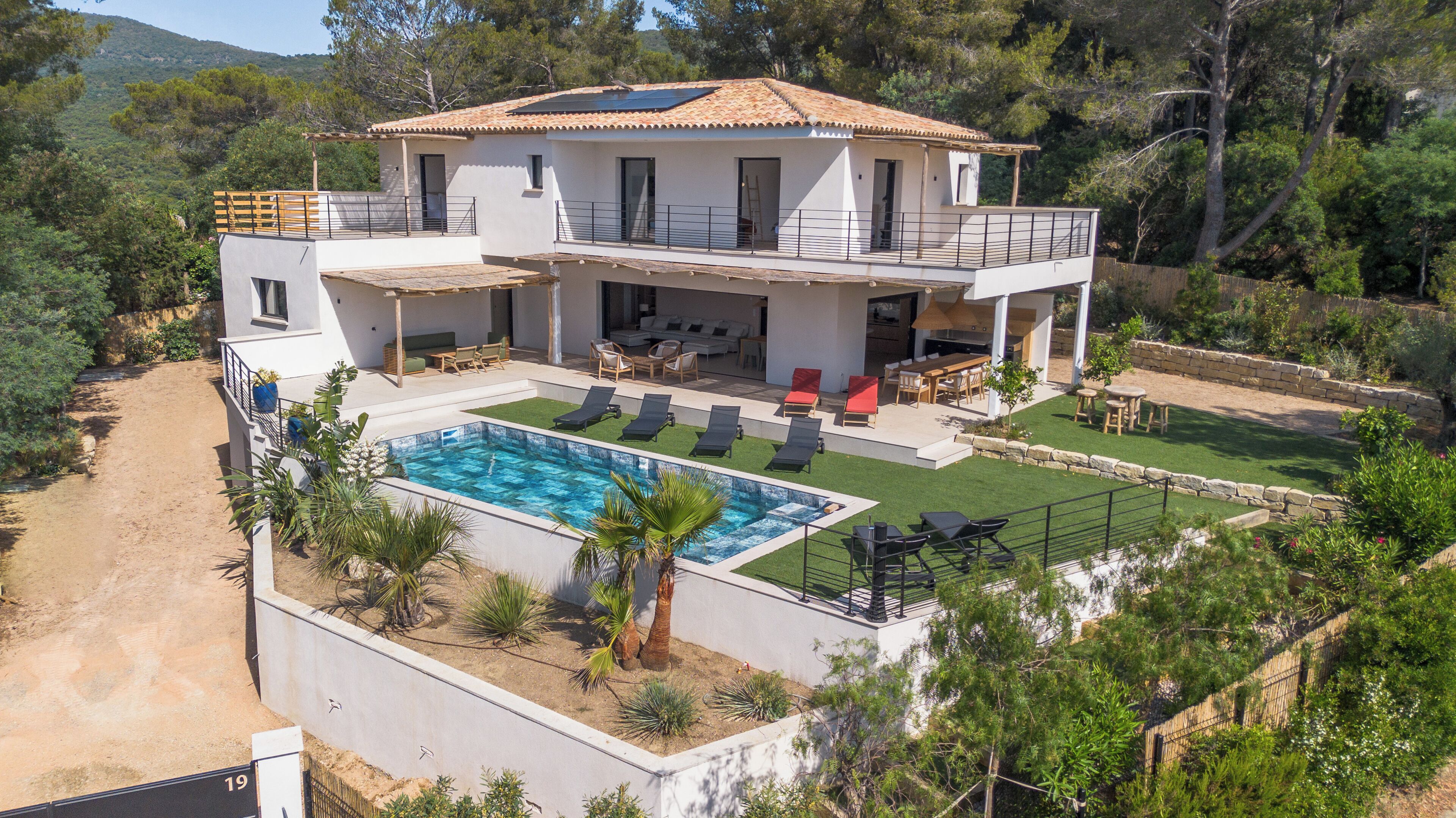 A two-story house with a swimming pool, outdoor seating, and a garden.