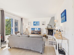 Ein modernes Wohnzimmer mit einer Couch, einem Fernseher, einem Kamin und Kunstwerken an den Wänden.
