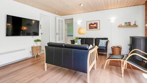 Uma sala de estar moderna com sofá, cadeiras, televisão, lareira e teto de madeira.