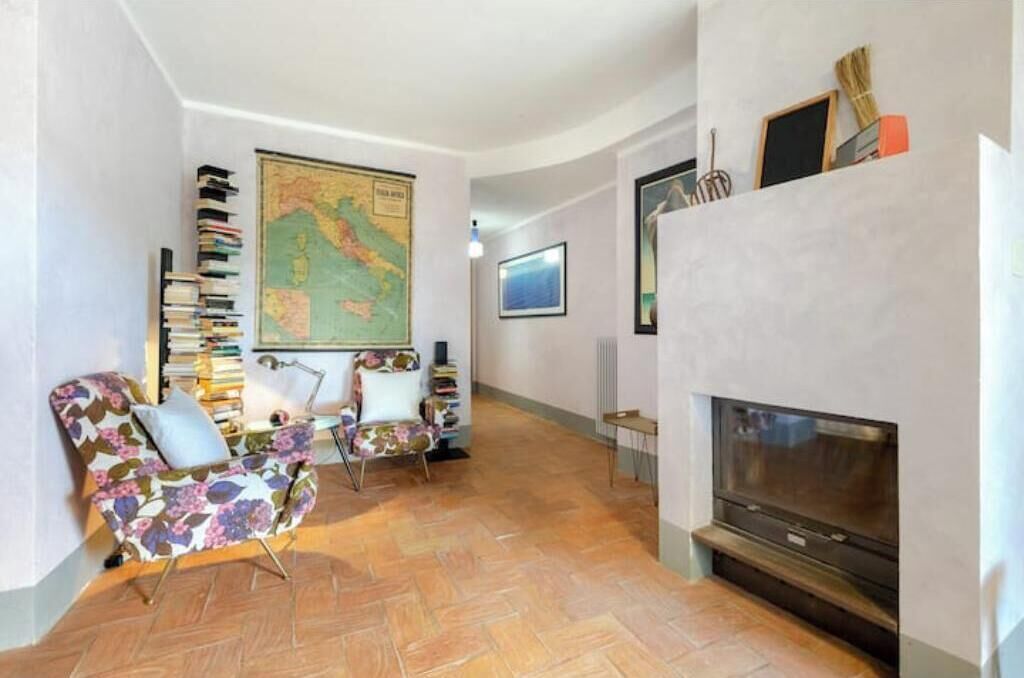 A living room with a fireplace, a large map on the wall, and two armchairs.
