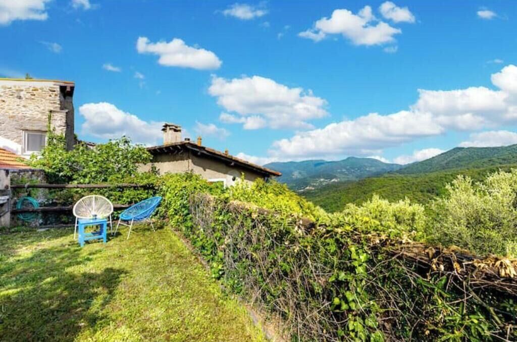 Un bâtiment en pierre doté d’un jardin et offrant une vue sur les montagnes.