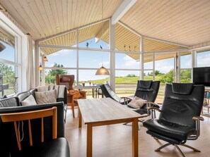 Ein geräumiges Zimmer mit hohen Decken, großen Fenstern und einem Holztisch.