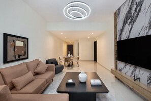 A modern living room with a sofa, coffee table, TV, and artwork. - Premium Stay in Duja Tower | Close to DIFC & Downtown (Dubai)