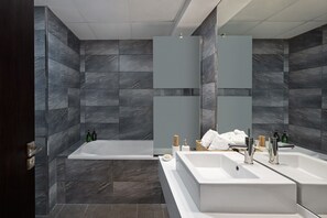 A modern bathroom with a large bathtub, two sinks, and a mirror. - Premium Stay in Duja Tower | Close to DIFC & Downtown (Dubai)