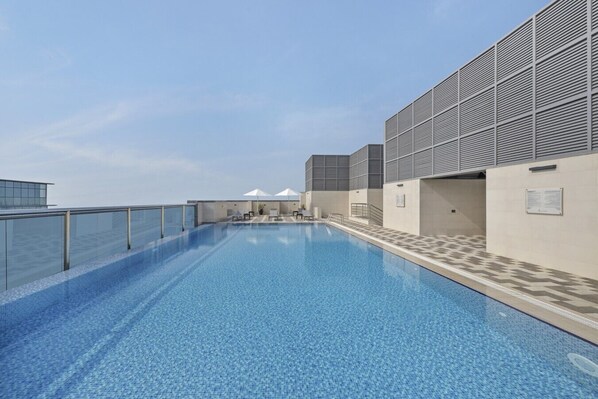 A rooftop swimming pool with a clear view of the sky, a glass balustrade, and a modern building facade. - Premium Stay in Duja Tower | Close to DIFC & Downtown (Dubai)