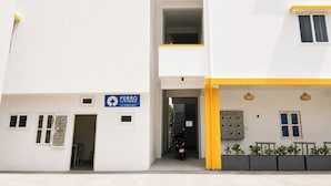 A multi-story building with a white facade, a blue sign indicating a business, and a yellow accent on the lower level. - Ferro Livingz (Bengaluru)