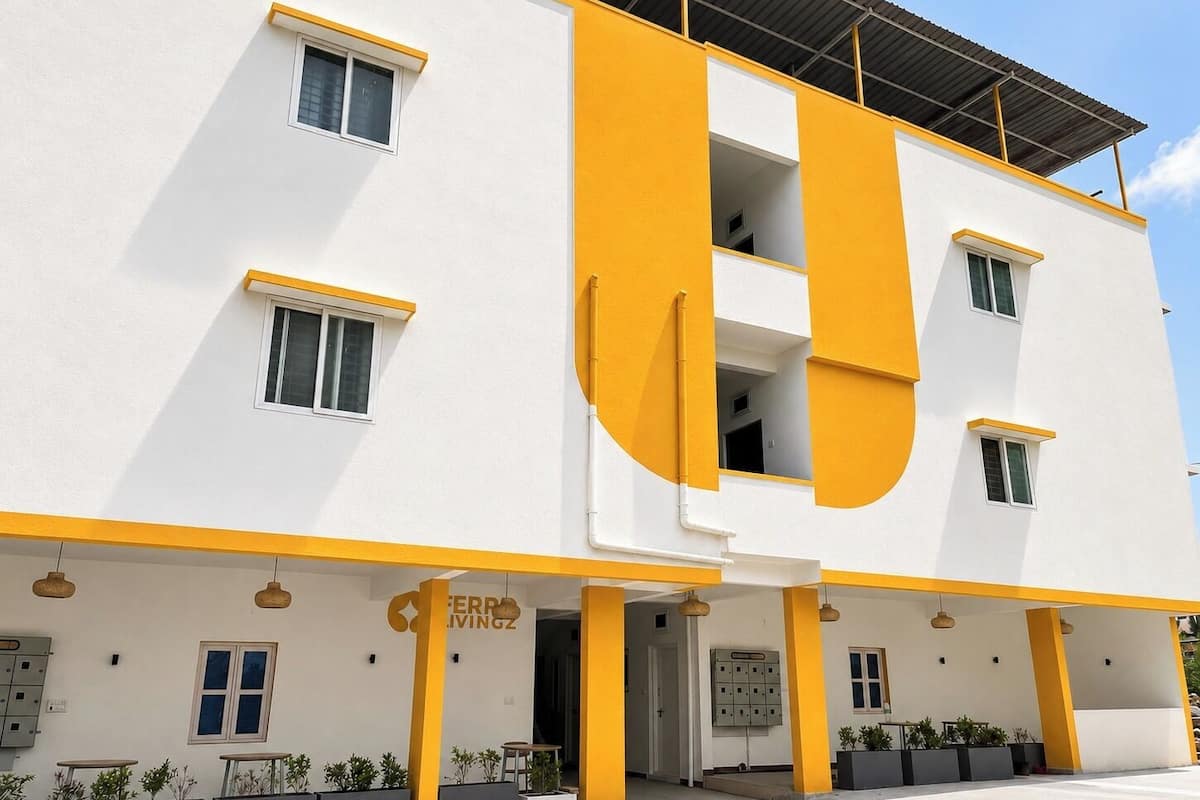 A modern building with a white facade and yellow accents, featuring multiple windows and a visible entrance.