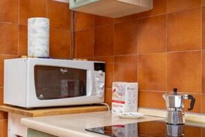 Une cuisine équipée d’un four à micro-ondes, d’une machine à café et d’un carton de lait posé sur le comptoir.