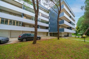 Ein mehrstöckiges Gebäude mit Balkonen, einem Parkplatz und einem begrünten Innenhof.