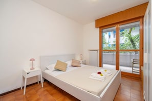 A bedroom with a bed, a nightstand, a window with a view, and a balcony. - Cozy and comfortable 50 square meters apartment, perfect for four people, located on the first floor of a building with an elevator (NOT accessible to disabled guests).The property is located in an extremely quiet area; its location allows our guests to  (Grado-Pineta)