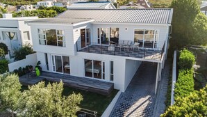 Een modern huis met twee verdiepingen, een balkon, grote ramen en een verharde oprit.