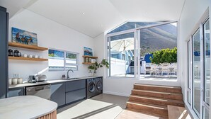 Een moderne keuken met inbouwapparatuur, houten planken en grote ramen met uitzicht op de omgeving.
