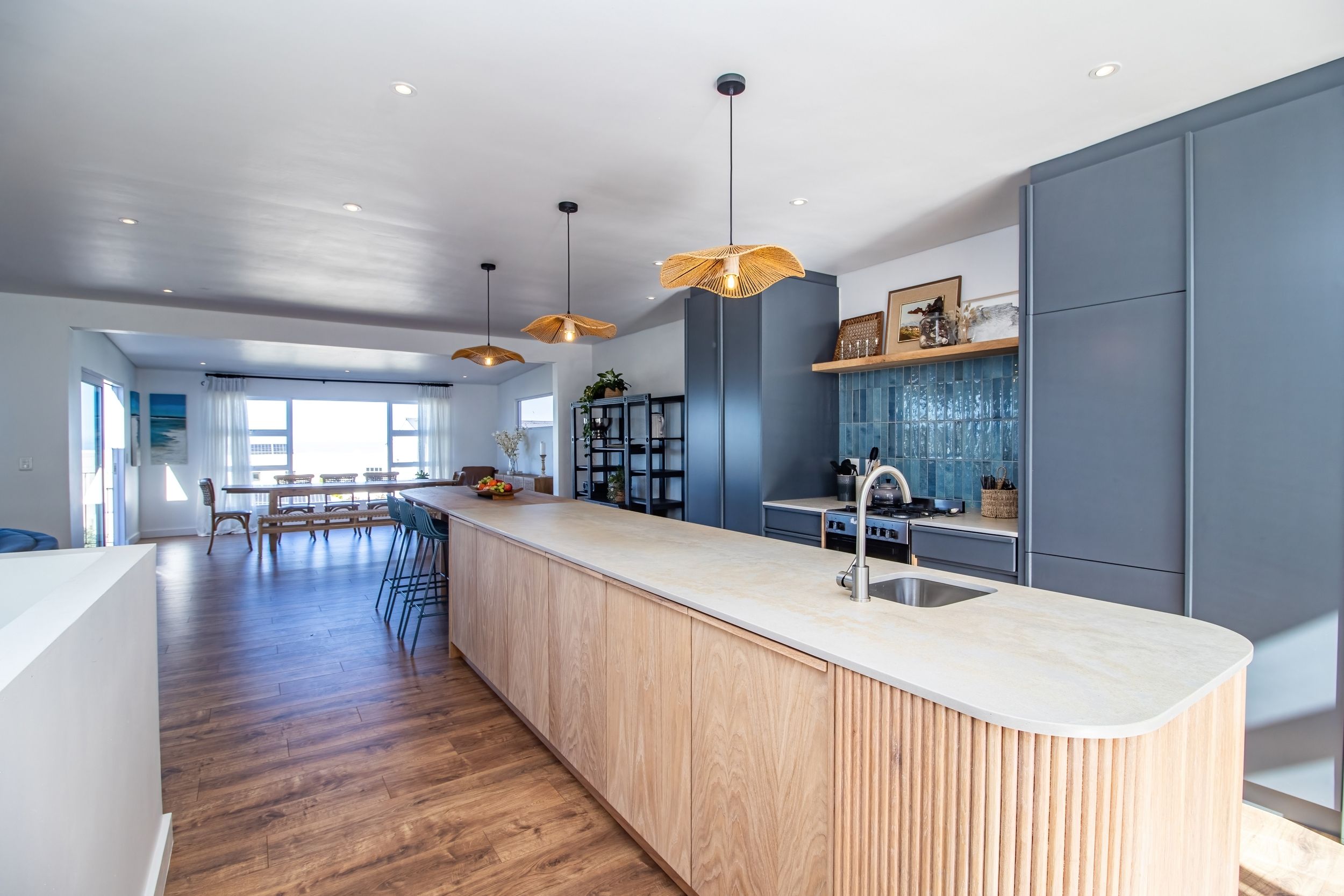 Een moderne keuken met een centraal eiland, hanglampen en uitzicht op de eetruimte.