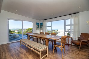 A spacious room with a large wooden dining table, wicker bench, and leather chairs.