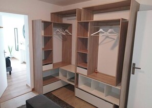 A walk-in closet with multiple shelves and hanging space, a bench, and a door. - Spacious 4-bedroom house. (Crach)