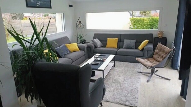 Una sala de estar moderna con un sofá, una mesa de centro, una silla y un ventanal grande.