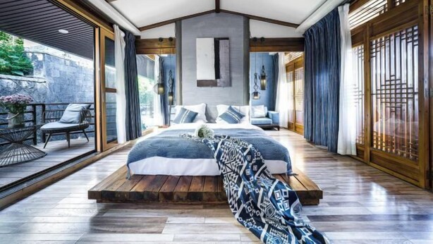 A modern bedroom with a large bed, a view of the outdoors, and a balcony with seating. - Yugui Hot Spring Holiday Hotel (Tengchong)