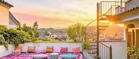 Una terraza en la azotea con un área de estar al aire libre con diseño, una escalera y vistas de la ciudad.