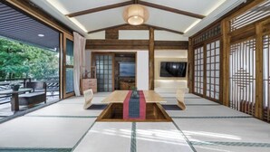 A traditional Japanese-style room with tatami flooring, a low wooden table, sliding doors, and a ceiling fan. - Yugui Hot Spring Holiday Hotel (Tengchong)
