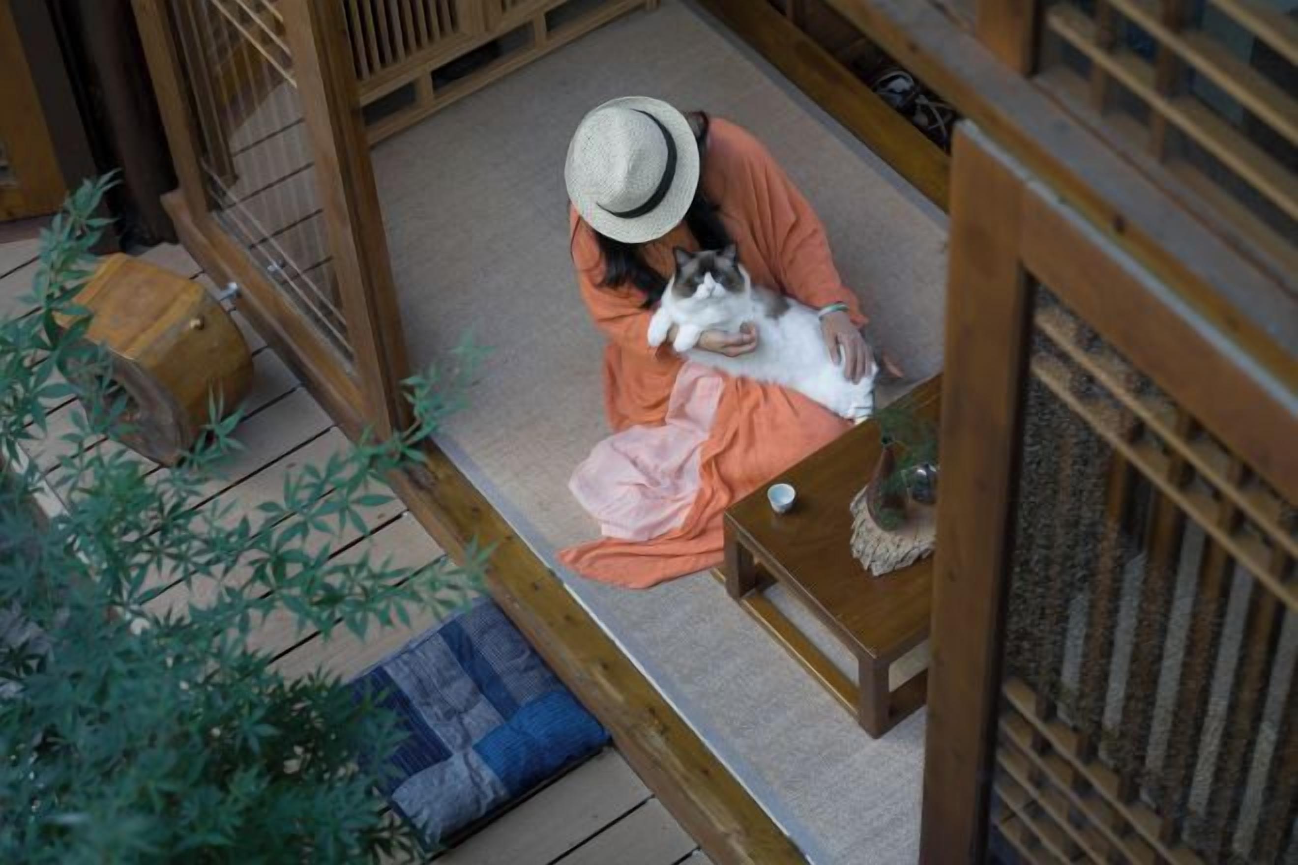 A person sitting on a tatami mat with a dog, in a traditional Japanese room with wooden sliding doors and a low table.