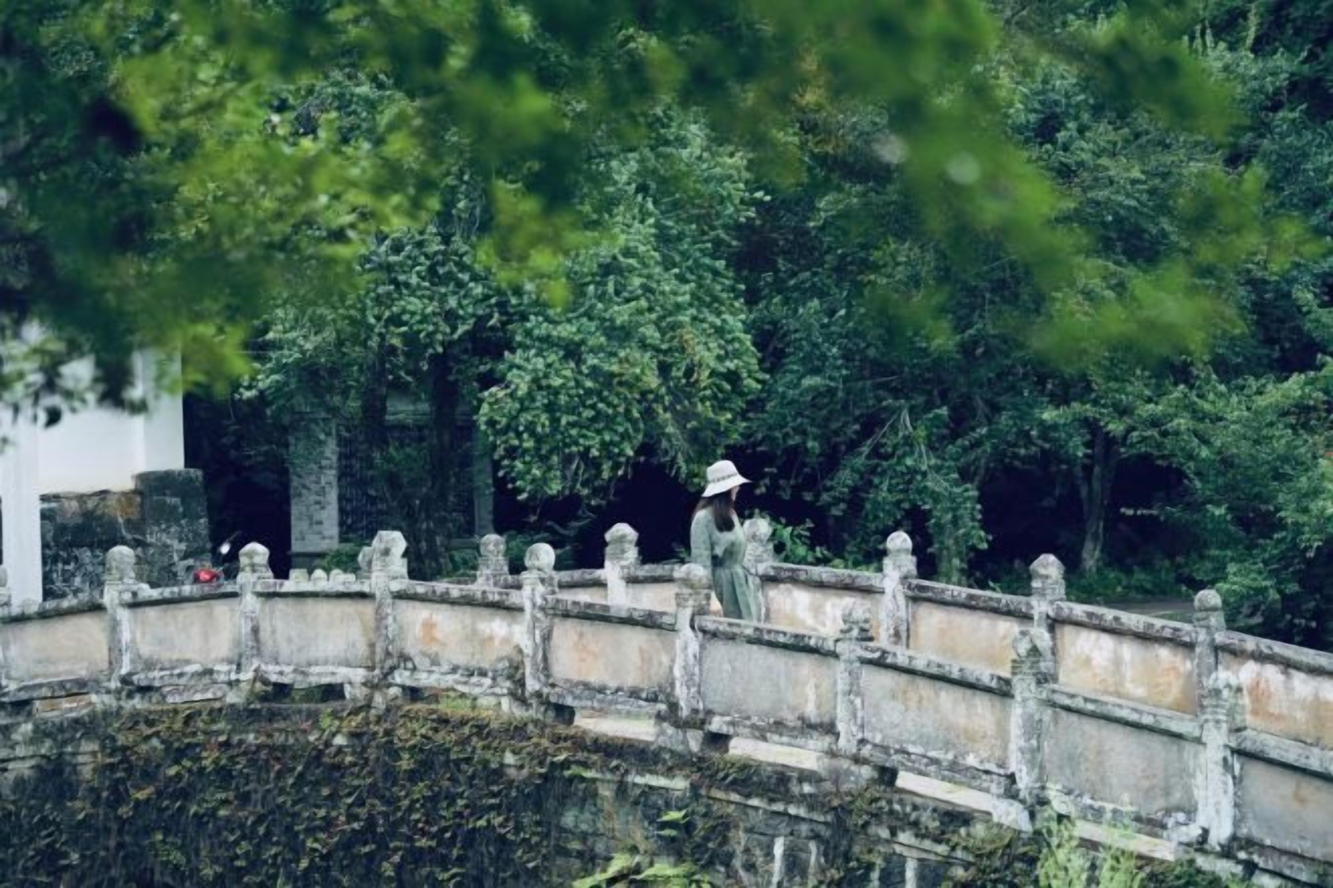 A stone bridge over a body of water with a person walking on it.