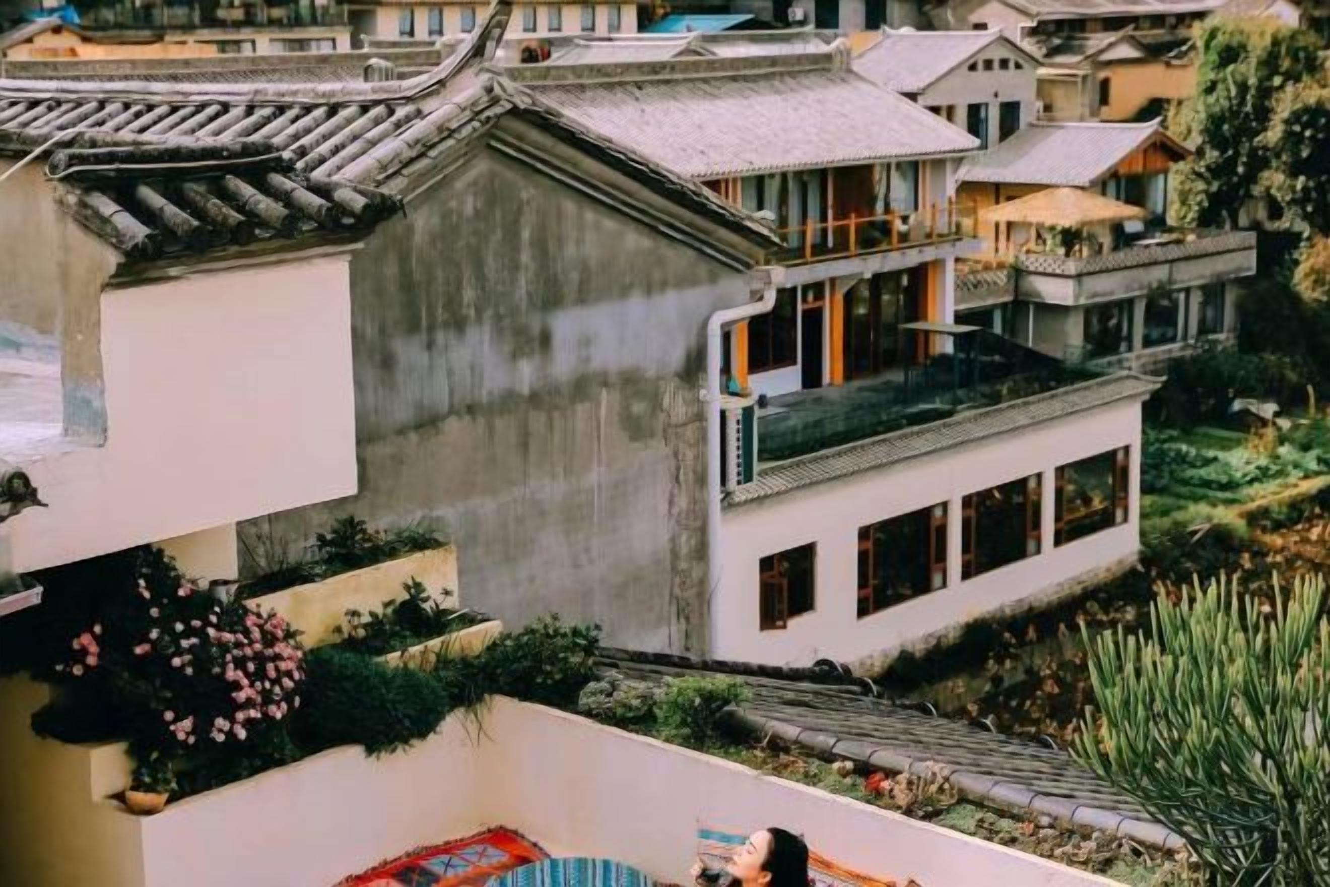 A traditional-style building with a balcony, a garden area, and a view of adjacent structures.