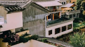 A traditional-style building with a balcony, a garden area, and a view of adjacent structures.
