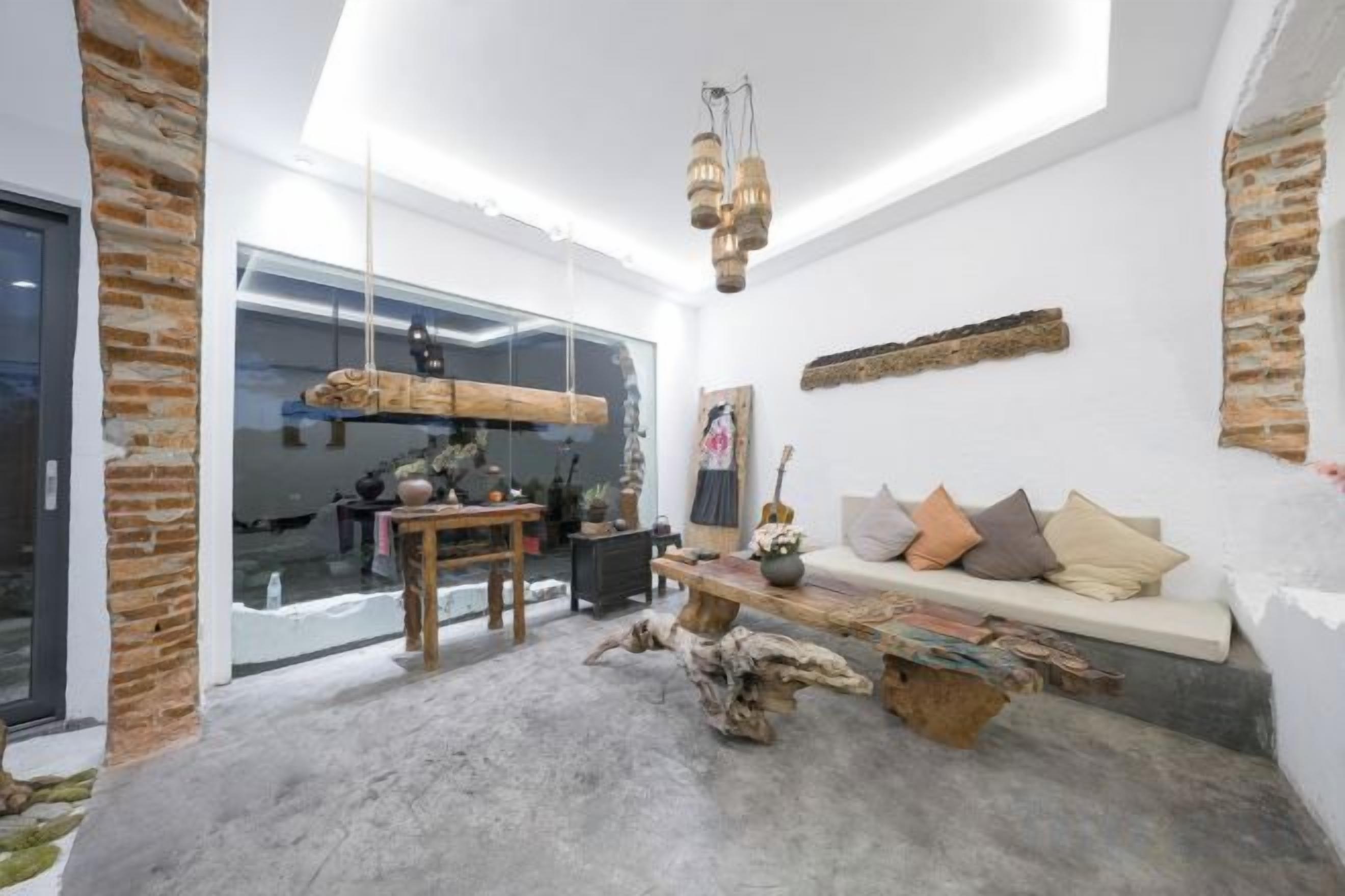 A modern living room with a glass wall, a wooden bench, and a hanging light fixture.