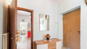 A hallway with a wooden door, a mirror, and a cabinet with a decorative item on top. - Hostdomus - Oltrefinale (Liguria)