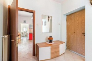 Um corredor com porta de madeira, um espelho e um armário com um objeto decorativo em cima.
