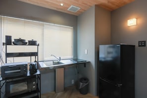 A compact kitchen with a microwave, toaster, and black refrigerator.