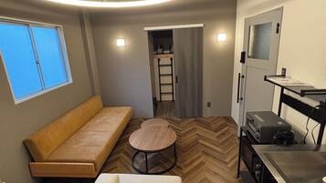 Un interior moderno con sofá, una mesa redonda, una kitchenette y un ventilador de techo.