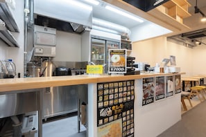 Interior de restaurante com balcão, quadros de menu e equipamentos de cozinha.