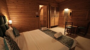 Una habitación de cabaña de madera con una cama, una silla y una mesita.