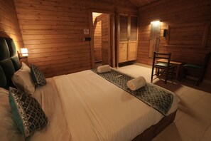 Quarto de cabana de madeira com uma cama, uma cadeira e uma pequena mesa.
