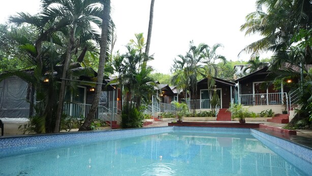 Una piscina rodeada de palmeras y cabañas de madera.
