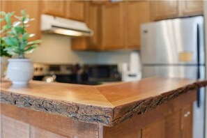 Une cuisine avec des meubles en bois, un réfrigérateur en acier inoxydable et un plan de travail agrémenté d’une plante.