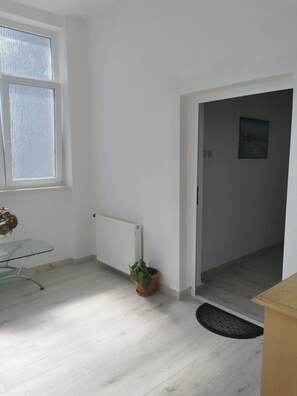 A room with a glass table, a potted plant, a radiator, and a door leading to another room. - Apartments Marija (Trogir)