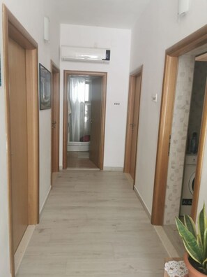 A hallway with wooden doors, a white air conditioning unit, and a potted plant. - Apartments Marija (Trogir)