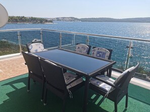 Ein Essbereich mit Tisch und Stühlen auf einer Terrasse mit Blick auf ein Gewässer.