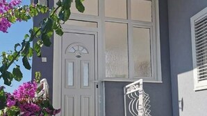 Ein Haus mit weißer Tür, einer kleinen Veranda und einem Metallgeländer.