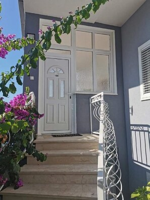 A house with a white door, a small porch, and a metal railing. - Apartments Marija (Trogir)