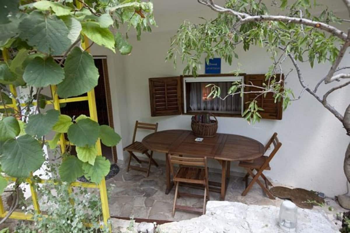 A round wooden table with four chairs, a small basket, and a sign on the wall.