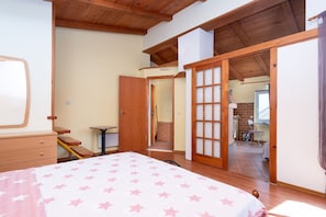 Ein Schlafzimmer mit einem Bett, Holzboden, Schreibtisch und Stuhl.