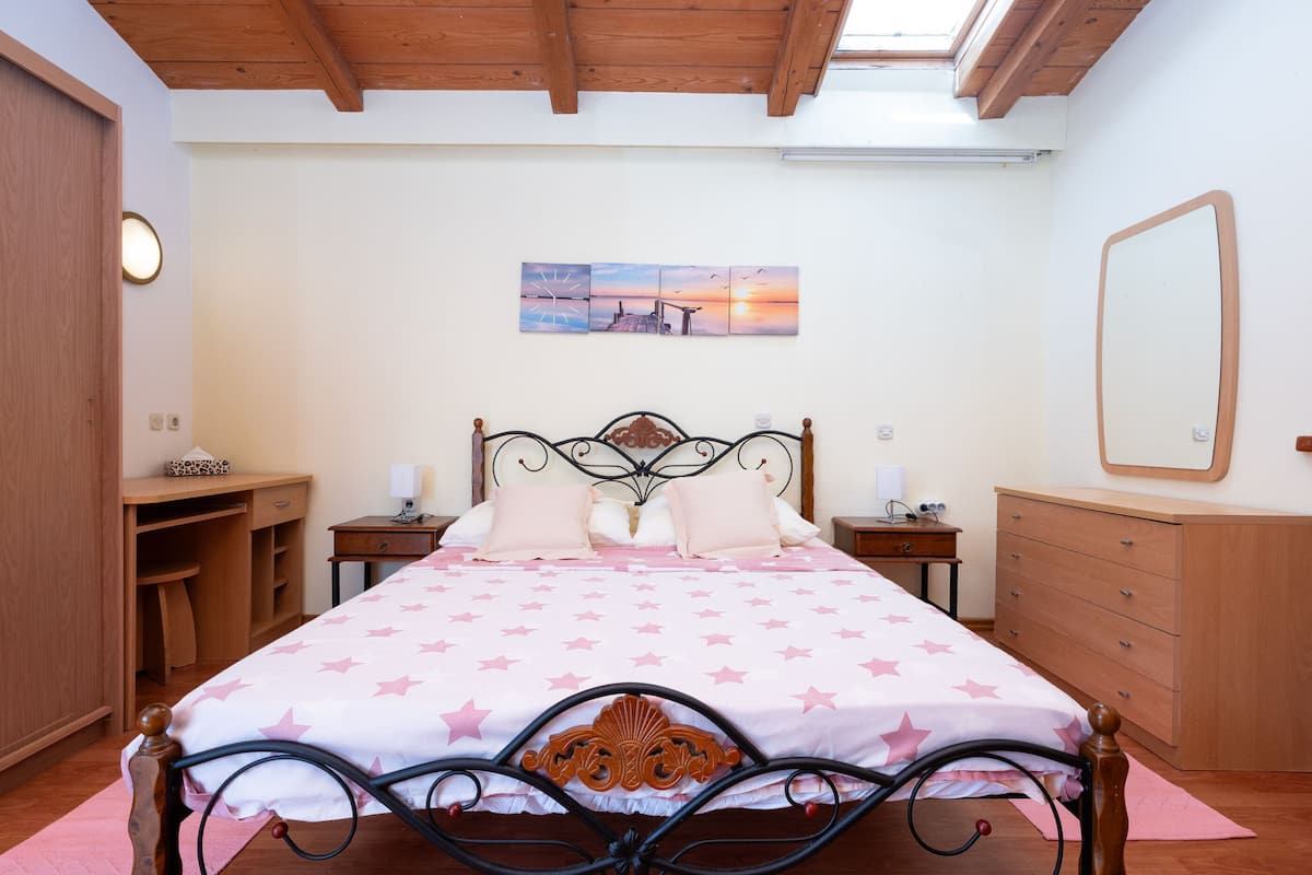 A bedroom with a bed, bedside tables, a wardrobe, a mirror, and a painting on the wall.