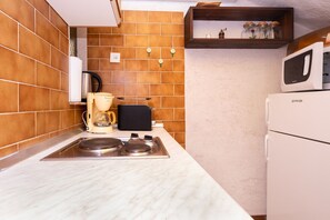Eine kompakte Küche mit integriertem Mikrowellenherd, einer Kaffeemaschine und einem Toaster.