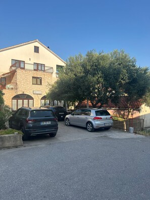 Ein Gebäude mit einer Steinauffahrt, einem Balkon und einem Baum davor.