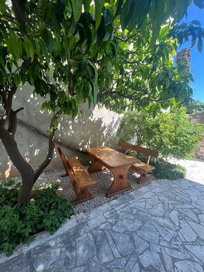 Ein Holzbänkchen und Tisch in einem Garten mit einem Steinweg.