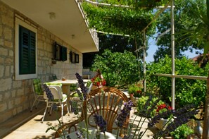 A stone building with a balcony, outdoor furniture, and a garden with lavender plants. - Apartment Jasna (Selca)